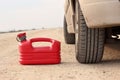 Red plastic fuel canister on dirt road with car Royalty Free Stock Photo