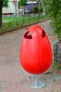 Red plastic garbage can in the park Royalty Free Stock Photo