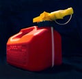 Red plastic gasoline can and yellow spout on black background