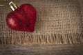 Red plastic heart placed on sack and wooden table