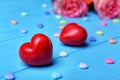 Red plastic hearts and roses on wooden background