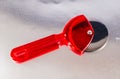 A red plastic pizza cutter sits on a silver surface Royalty Free Stock Photo