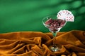 Red plastic poker chips lie in a glass margarita glass on a brown velvet cloth. A fan of small playing cards on the rim of a glass Royalty Free Stock Photo