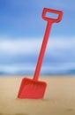 Red plastic toy spade in sand Royalty Free Stock Photo