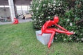 Red plastic womae sculptures. Blooming tree background.