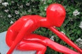 Red plastic woman sculpture. Blooming tree background.