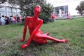 Red plastic woman sculpture. It sits on the green grass field.