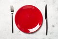 Red plate and cutlery on light stone table. Royalty Free Stock Photo