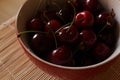 Red plate with dark cherries on the table Royalty Free Stock Photo