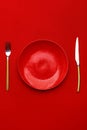 Red plate, knife and fork on a red table. Top view. Copy space Royalty Free Stock Photo