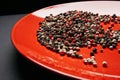 Red plate with a mixture pepper on a dark background