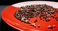 Red plate with a mixture pepper on a dark background