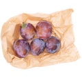 Red plums, fruit, on ecologically sound brown paper bag, isolated on white background.