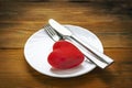 Red Plush Heart with Fork and Knife in Finished the Meal Position on a White Plate. Wooden Background. Minimalist Healthcare, Royalty Free Stock Photo