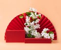 Red podium paper oriental fan flowering branch with buds pink pastel background