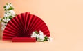 Red podium paper oriental fan flowering branch with buds pink pastel background