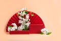 Red podium paper oriental fan flowering branch with buds pink pastel background