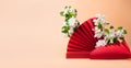 Red podium paper oriental fan flowering branch with buds pink pastel background