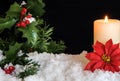 Red Poinsettia flower with lit candle and Mistletoe in snow. Christmas Background with holiday theme Royalty Free Stock Photo
