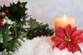 Red Poinsettia flower with lit candle and Mistletoe in snow. White Christmas Background with holiday theme Royalty Free Stock Photo