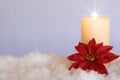 Red Poinsettia flower with lit candle in snow. White Christmas Background with holiday theme Royalty Free Stock Photo