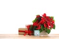 Red Poinsettia in pot and gifts on wooden table, space for text. Christmas traditional flower Royalty Free Stock Photo