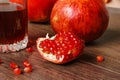Red pomegranate fruits and glass with juice on a dark surface