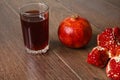 Red pomegranate fruits, seeds and glass with juice on a dark surface
