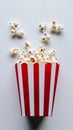 A red popcorn box with scattered kernels on a white background, movement and snack-time fun Royalty Free Stock Photo