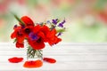 Red poppies, cornflowers, ears of green wheat, chamomile in small vase on white wooden table on summer blur natural background Royalty Free Stock Photo