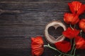 Red poppies flowers with wooden heart on dark wood background. Royalty Free Stock Photo