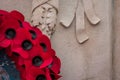 Red poppy wreaths laid at the bottom of a war memorial for Remembrance day