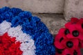 Red poppy wreaths laid at the bottom of a war memorial for Remembrance day