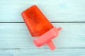 Red popsicle on bright blue wooden table, summer food