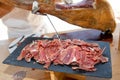 red pork cured ham cut by hand chef professional cutter carving slices from whole bone in serrano hams