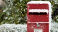 Close up of a Red post box at Christmas covered with falling snow Royalty Free Stock Photo