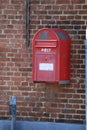 a red post box mounted to a brick wall next to a parking meter Royalty Free Stock Photo