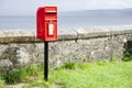 Red post box in Scottish rural location brightly lit under dark sky Royalty Free Stock Photo