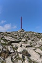 Red post guiding the way on Babia GÃÂ³ra mountain trail, vertical view from bottom with rocks and sky visible.