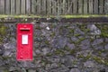 Red post mail box in stone wall