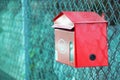 Red postbox hanging in front of the fence Royalty Free Stock Photo