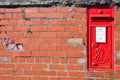 Red postbox mounted in a brick wall