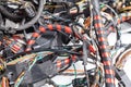 A red power channel rewound with black electrical tape close-up on a background of multi-colored wires twisted together. Tangled