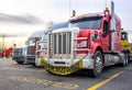 Red powerful big rig semi truck with oversize load sign on the grill guard bumper standing with loaded semi trailer at row on the Royalty Free Stock Photo