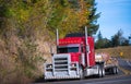 Red powerful big rig semi truck and step deck trailer with cargo Royalty Free Stock Photo