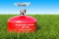 Red primus stove on the green grass against blue sky, 3D rendering