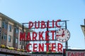 Red Public market sign with a clock before the blue skyline in Seattle