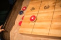 Red puck barely in the 4 point zone of a shuffleboard table