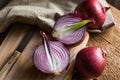 Red or purple onion cut in half, wood breadboard, linen towel, knife, kitchen table by window