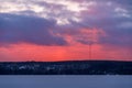 Red and purple sky over the frozen lake after the sunset in Finland with radio tower in the distance